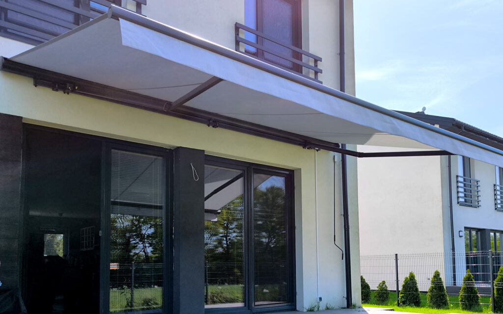 Markiza tarasowa Solaro z aluminiowymi ramionami zamontowana na tarasie domu jednorodzinnego