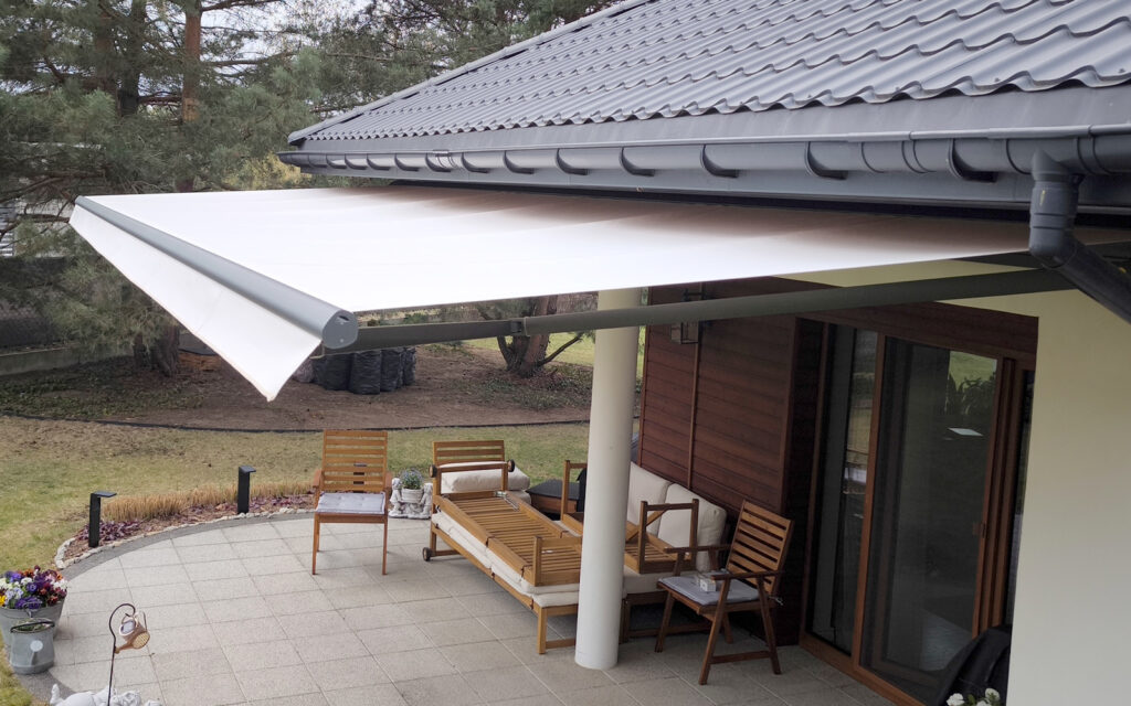 Markiza tarasowa Solaro z aluminiowymi ramionami zamontowana na tarasie domu jednorodzinnego