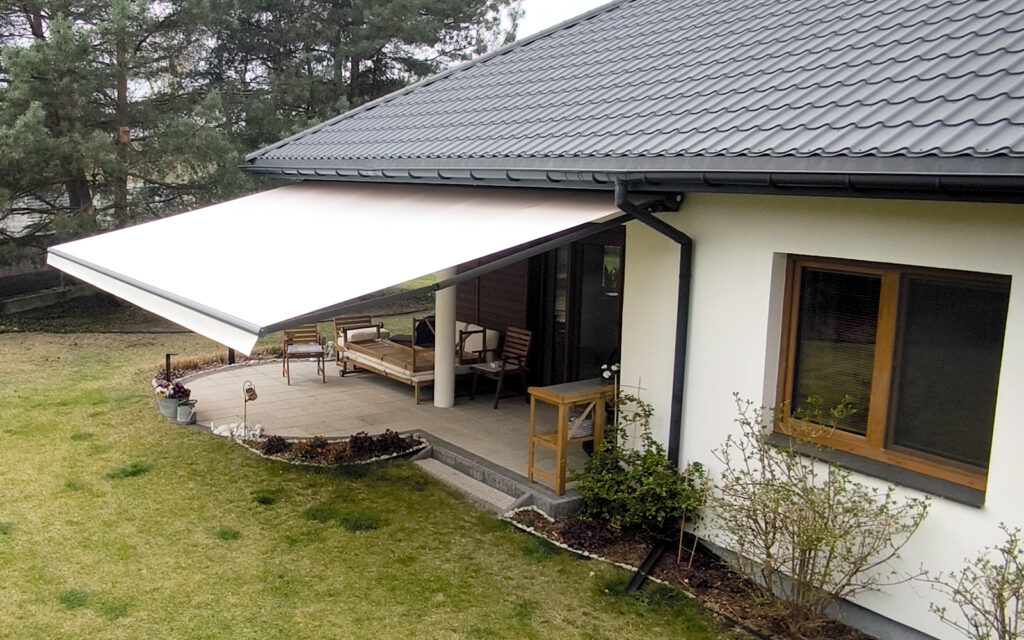 Markiza tarasowa Solaro z aluminiowymi ramionami zamontowana na tarasie domu jednorodzinnego